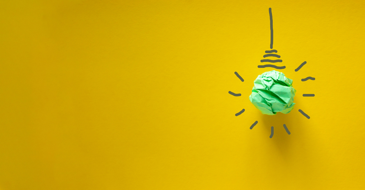 Crumpled Green Paper Light Bulb on Yellow Background